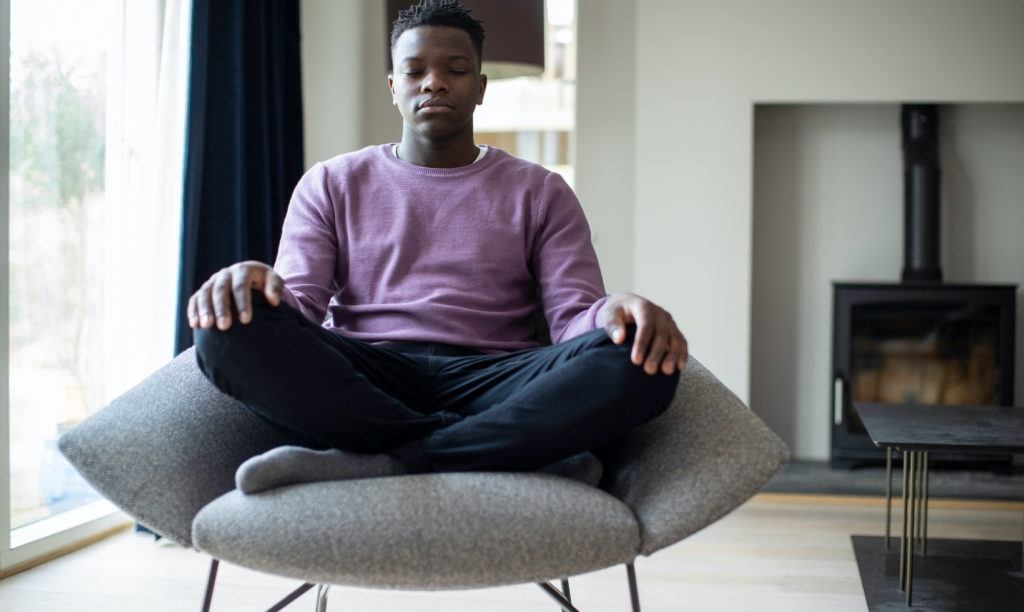 About 1 Young man meditating seated in chair